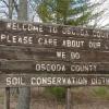 Before: The well-weathered Conservation District sign located on M-72 west of McCollum Lake greeted folks entering Oscoda County.